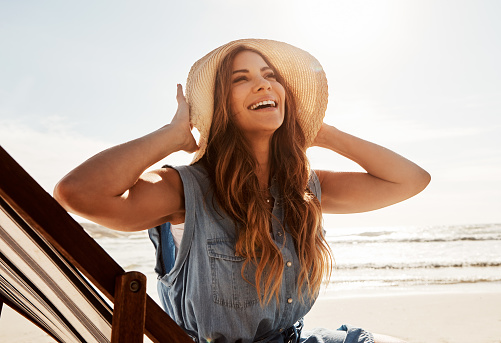 Shot of a young woman relaxing on a lounger at the beach