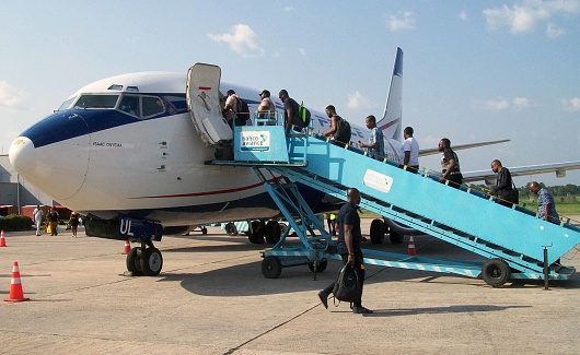 Maun International Airport, Botswana - December 19th 2022:  Passengers boarding a small jet aircraft, a Embraer190 ZS-YAY from FlyAirLink on the open tarmac in Maun Airport