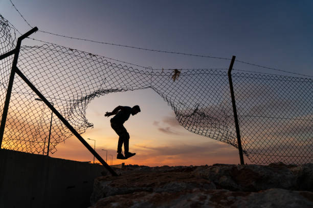 istock Refugee man running behind fence, 1193701327