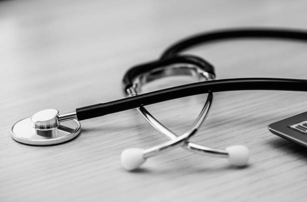 Macro black stethoscope on the table, close up view. Horizontal, black and white image