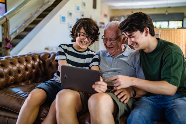 großvater und enkel nutzen tablet zusammen - senior adult digital tablet domestic life learning stock-fotos und bilder