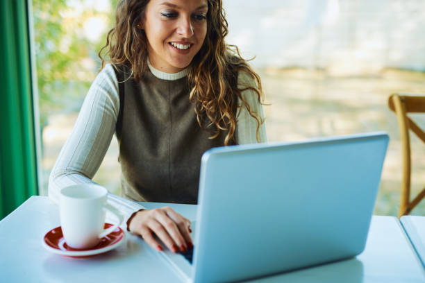 istock Attractive young curly brunette looking at her notebook and smiling 1193703753