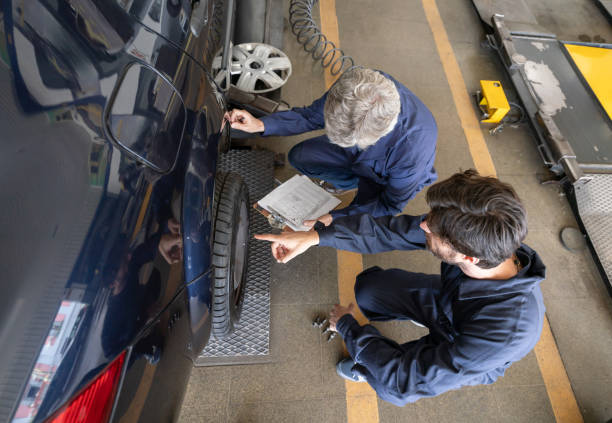 Team of mechanics checking car alignment at an auto repair shop Team of mechanics checking car alignment at an auto repair shop - High angle view car mechanic top view stock pictures, royalty-free photos & images