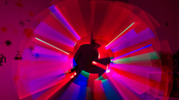 Boy playing in his room with lightsaber in various colors with figures of space invaders on the wall Boy playing in his room with lightsaber in various colors with figures of space invaders on the wall. Lightpaint effect neon bedroom stock pictures, royalty-free photos & images