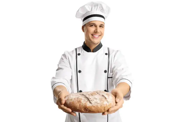 Young male chef holding a home made bread isolated on white background
