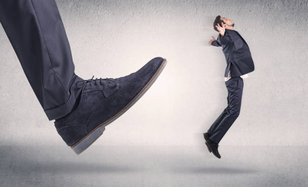 istock Small businessman kicked by big shoe 1193707361