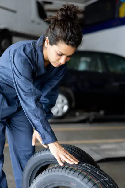Latin american female mechanic checking new tires for a car at an autorepair shop - Automobile industry concepts