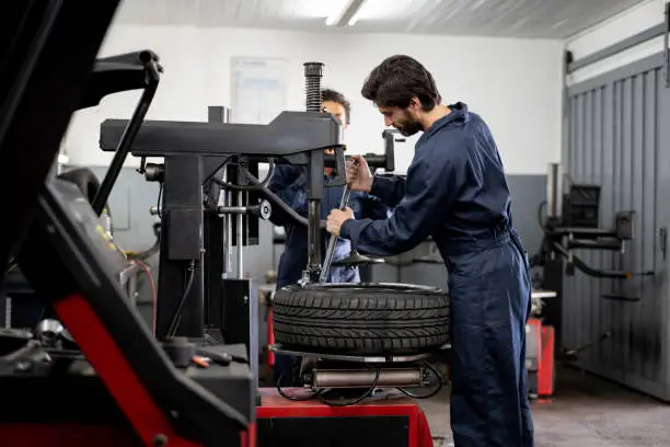 Team of mechanics at an autorepair shop fixing a punctured tire - Service concepts