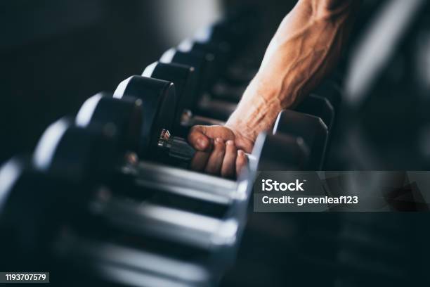 Rows Of Dumbbells In The Gym With Hand Stock Photo - Download Image Now - Gym, Health Club, Weights