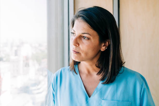 Thoughtful nurse by window in hospital