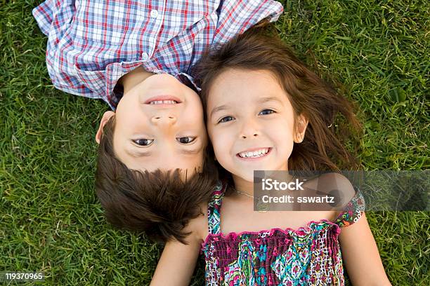 Two Young Siblings Lying On The Grass Smiling Together Stock Photo - Download Image Now