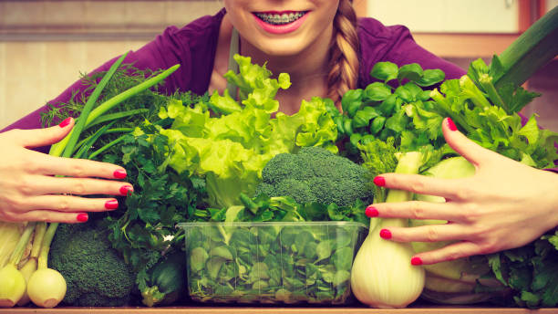 istock Smiling woman in kitchen with green vegetables 1193710753
