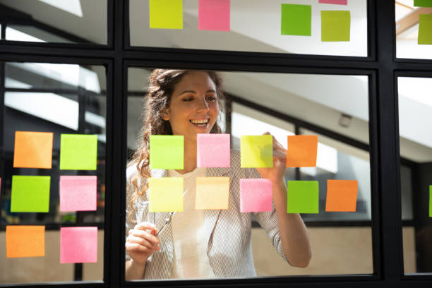 istock Happy female scrum master writing tasks on sticky paper notes. 1193713008