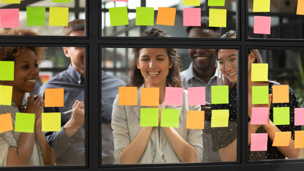 istock Happy mixed race group looking at notes on glass board. 1193713029