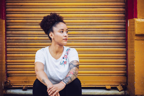 istock Thoughtful woman sitting against closed shutter 1193713270