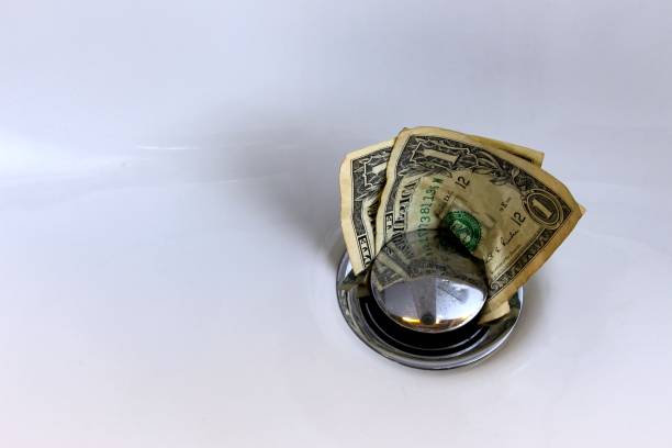 Money going down the drain Money in a white sink going down the drain, business concept, selected focus on the money oops stock pictures, royalty-free photos & images