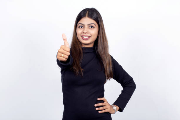 retrato de mujer de negocios india confiada gestituando pulgares hacia arriba contra fondo blanco - confidence toothy smile thumbs up ok sign fotografías e imágenes de stock