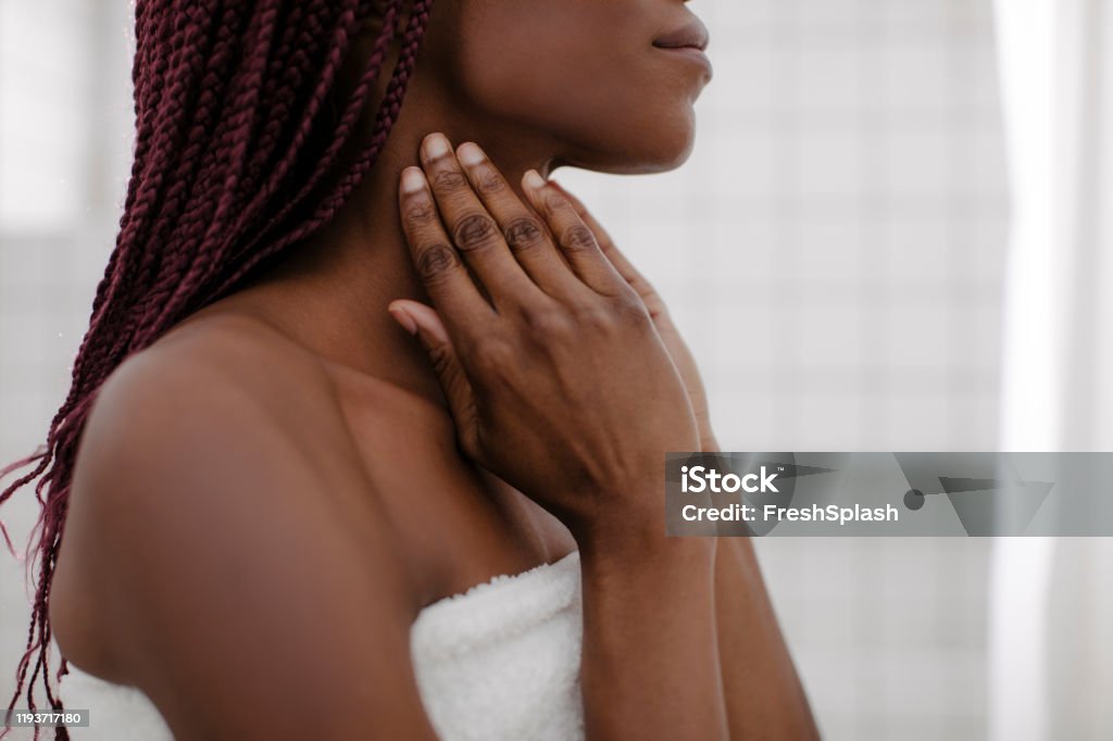 A Woman Touching her Neck Unrecognisable young African woman massaging her neck after shower. Neck Stock Photo