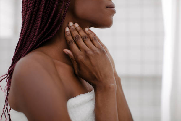 A Woman Touching her Neck Unrecognisable young African woman massaging her neck after shower. neck stock pictures, royalty-free photos & images