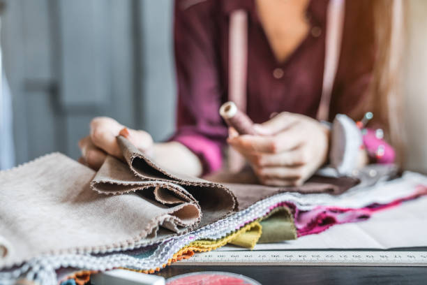 fim acima do desenhador da mulher que escolhe a cor da tela para a coleção nova - amostra de tecido têxtil - fotografias e filmes do acervo