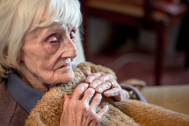 An elderly woman feeling cold at her home during the winter months.