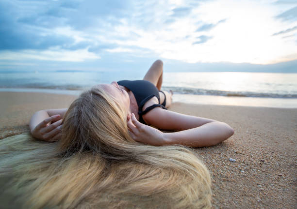 istock Woman Lying Down On Beach Against Sky 1193723706