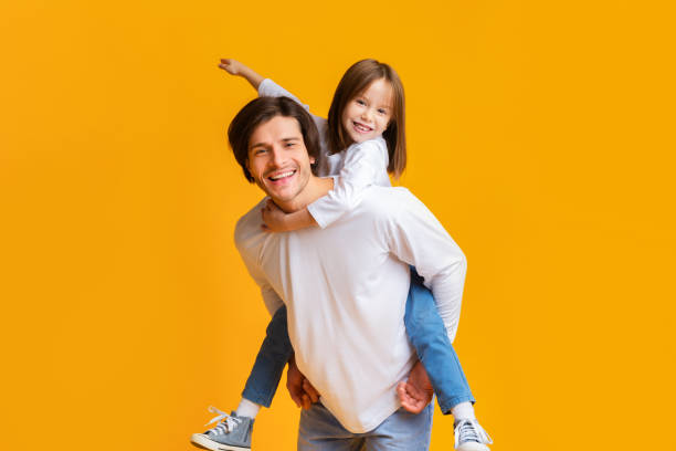 istock Joyful father and daughter playing together over yellow background 1193725237