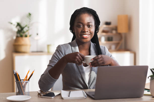 istock Smiling african american secretary drinking coffee at workplace in modern office 1193725250