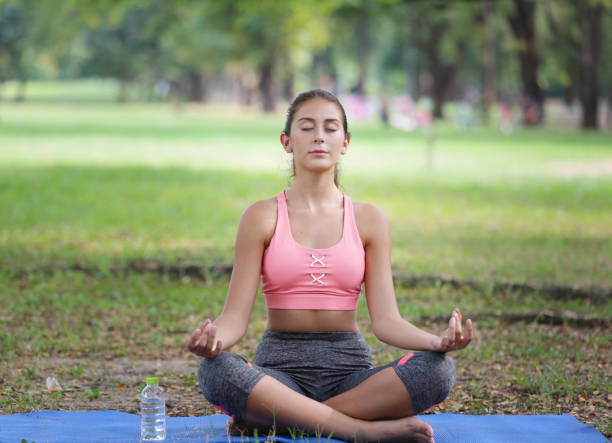 istock Young Woman Sitting On Exercise Mat Doing Yoga At Park 1193725540