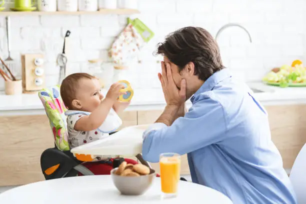 Photo of Cheerful daddy playing with cute baby son in kitchen