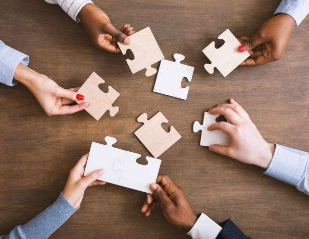 istock Group of business people assembling jigsaw puzzle together 1193728812