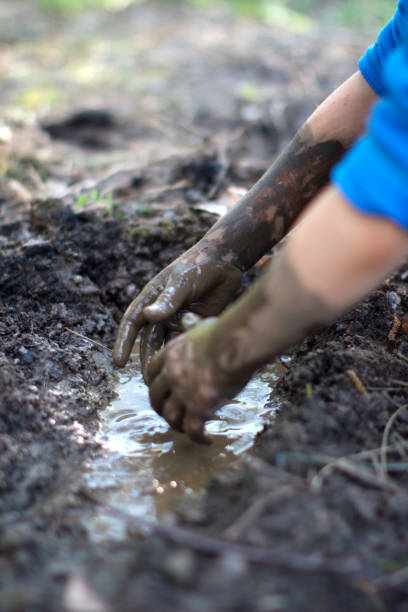 istock Fun child playing in mud pond created with hands, backyard 1193729717