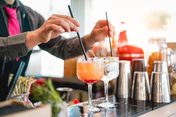 Young bartender making cocktails at bar counter - Barman serving drinks - Work, passion and mixologist concept Young bartender making cocktails at bar counter - Barman serving drinks - Work, passion and mixologist concept pub bar counter bar men stock pictures, royalty-free photos & images