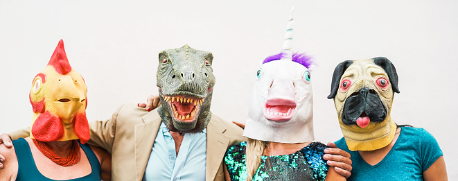 Happy family wearing different carnival masks - Crazy people having fun wearing on chicken, t-rex and unicorn mask - Concept of bizarre, humor and masquerade holidays lifestyle party