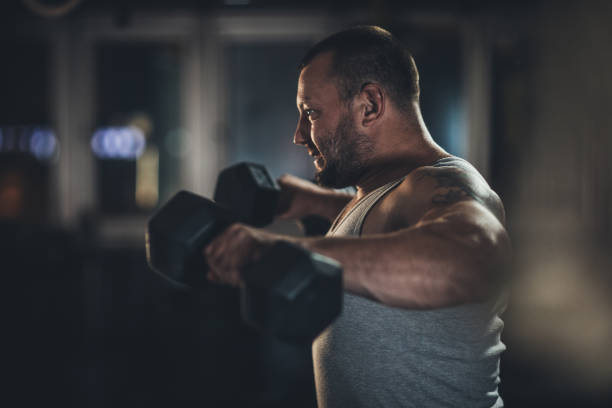 istock Man exercising in gym with dumbbells 1193732350
