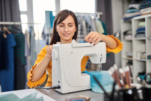 istock Dedicated seamstress sitting in her studio and inserting thread in sewing machine. 1193733811