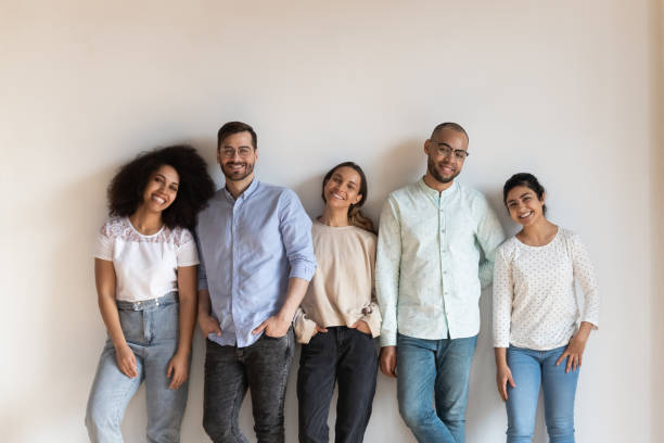 istock Smiling mixed race young friendly people standing near white wall. 1193735021