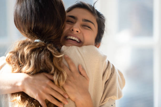 Happy mixed race girl cuddling smiling indian female friend. Head shot close up happy mixed race girl cuddling smiling indian female friend. Overjoyed excited best buddies emracing hugging, greeting each other with success, true strong friendship concept. embracing stock pictures, royalty-free photos & images