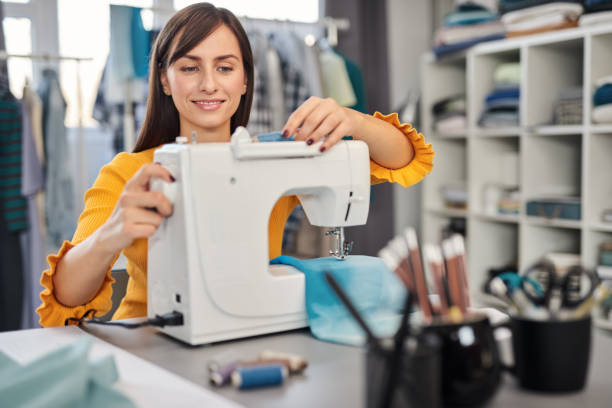 istock Dedicated seamstress sitting in her studio and inserting thread in sewing machine. 1193735054