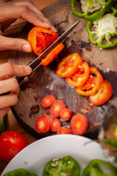 istock Hands chopping fresh red tomato on chopping board. 1193736078