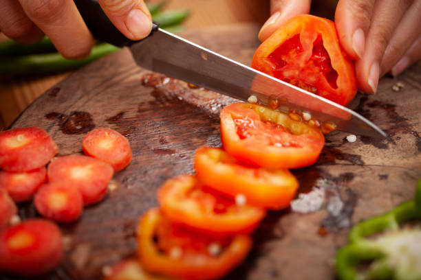 istock Hands chopping fresh red tomato on chopping board. 1193736192