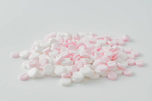 istock Pink and white pills on a light background. Medical pharmacy concept 1193736254