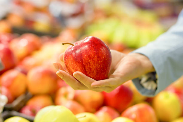 istock Woman's hand choosing apple at supermarket 1193740798