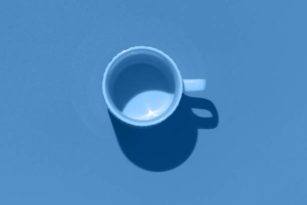 Empty tea cup on blue background. Coffee mug from above. Minimal concept, dark shadow. Flat lay, top view. Trendy color of the year 2020.