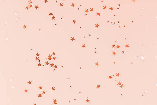istock Golden stars glitter confetti on peach colored background. Festive backdrop. 1193742142
