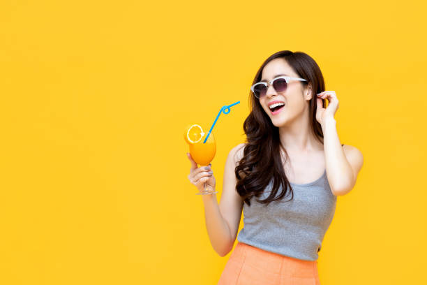 menina asiática saudável no equipamento do verão que bebe o suco de laranja - sunglasses women smiling portrait - fotografias e filmes do acervo