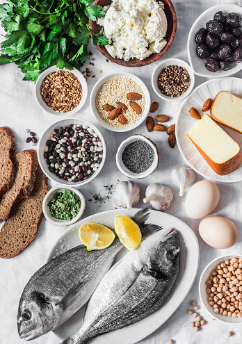 Products rich in calcium - fish seafood, cottage cheese, garlic, poppy seeds, nuts, sesame, cheese, beans, eggs on a light background, top view. Balanced food background