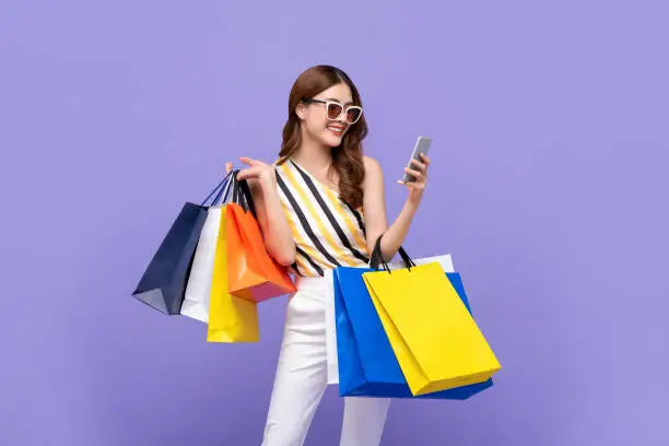 Photo of Beautiful Asian woman carrying colorful bags shopping online with mobile phone