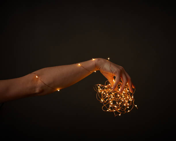 istock A woman's hand holds bright Christmas lights on a black background with space for text. Christmas 1193750491