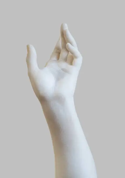 side view closeup of white stone marble statue hand reaching out to the heavens isolated on grey background